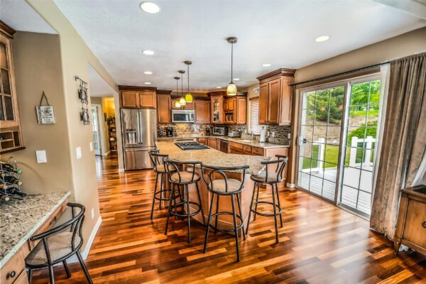 Spacious modern kitchen featuring wooden cabinets, granite countertops, and a large island with bar stools.